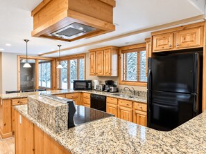 A modern kitchen with granite countertops, wooden cabinets, a black refrigerator, and built-in appliances. - Park City 4BR Condo | Private Hot Tub + Pool & Sauna | Walk or Shuttle to Park City Mountain (Park City)