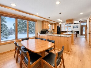 A modern kitchen with wooden cabinets, a central island, and large windows.
