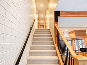 A staircase with a wooden handrail and carpeted steps leading to a kitchen area with wooden cabinets and a microwave. - Park City 4BR Condo | Private Hot Tub + Pool & Sauna | Walk or Shuttle to Park City Mountain (Park City)