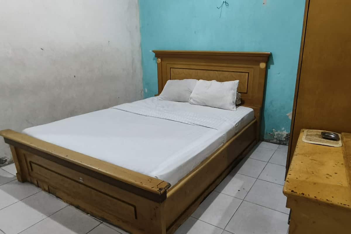 A single bed with a wooden frame and white bedding in a room with a blue wall and a wooden cabinet.