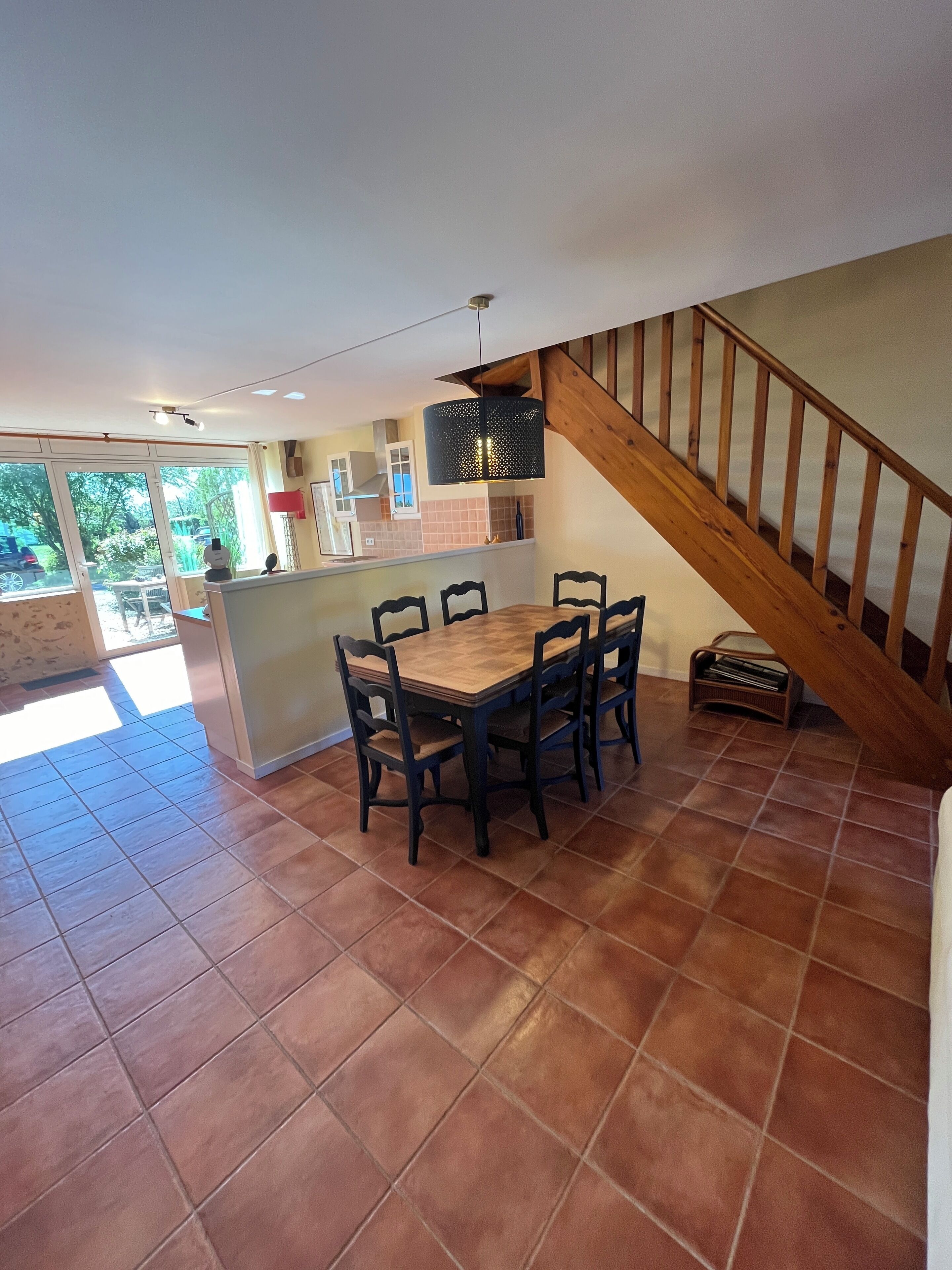 A spacious kitchen with a wooden table and chairs, a staircase, and a view of the outdoors.
