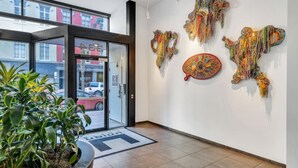 Een hotellobby met een glazen entree, een potplant en abstracte wanddecoratie.
