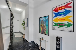 Un pasillo con piso de mármol negro, paredes blancas y un cartel con un pez colorido.