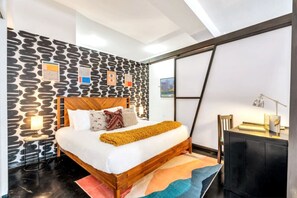 Une chambre moderne avec un lit en bois, un mur à motifs et un bureau avec une lampe.