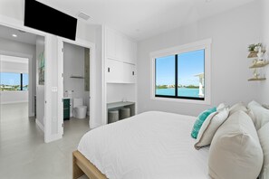 A modern bedroom with a large bed, a view of the sea, and a walk-in closet. - Luxury Seaside Escape ~ Pool ~ Dock ~ Scenic Views (Marathon)