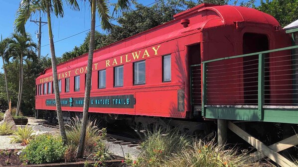 Een rode goederenwagon van de Florida East Coast Railway met de tekst 'CRANE POINT HARBOR & NATURE TRAILS'.