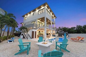 A multi-story house with a pool, outdoor seating, and a fire pit.