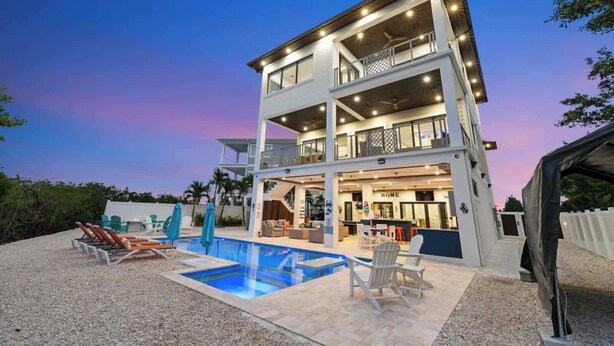 A multi-story building with a pool, outdoor seating, and a visible entrance labeled 'HOME'. - Luxury Seaside Escape ~ Pool ~ Dock ~ Scenic Views (Marathon)