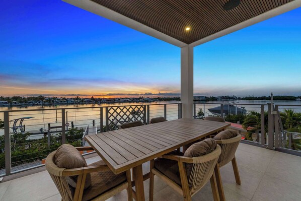 Ein Holztisch und -stühle auf einem Balkon mit Blick auf einen Fluss und eine Stadtansicht.