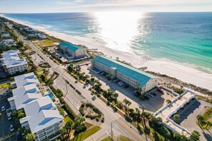 Vista aérea de un hotel costero con varias construcciones, un estacionamiento y acceso a la playa.