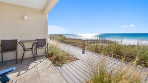 A balcony with wicker furniture overlooking a beach. - Crystal Sands110A • Luxe Remodel, Steps to the Sand (Destin)