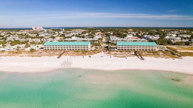 An aerial view of a coastal hotel with two large buildings, a sandy beach, and clear turquoise waters. - Crystal Sands110A • Luxe Remodel, Steps to the Sand (Destin)