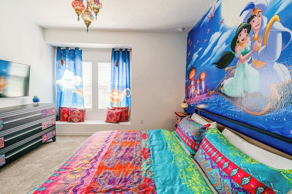 Een slaapkamer met een groot bed, een kapstok, een televisie en een raam met gordijnen.