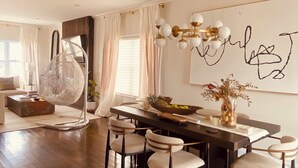 A modern dining area with a wooden table, white chairs, and a chandelier. - Private Room &Bathroom, Quaint Beach Town, Free local beaches, Ferry to NYC (Highlands)