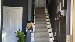 A staircase with a patterned carpet, a white door, a potted plant, and a dark wooden door. - Private Room &Bathroom, Quaint Beach Town, Free local beaches, Ferry to NYC (Highlands)