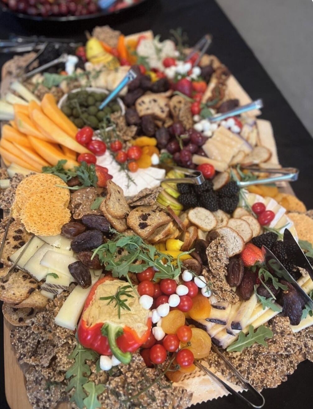 Une planche de charcuterie accompagnée de divers fromages, fruits et fruits secs.