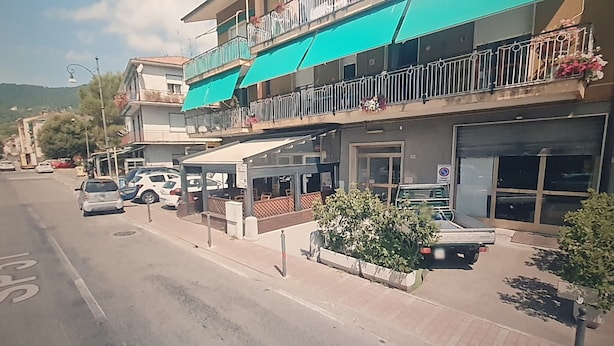 Une vue de rue avec un immeuble doté de balcons ornés de balustrades et de plantes en pot.