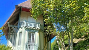 Una casa tradicional con entramado de madera y un balcón, con una pequeña mesa y sillas afuera.