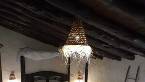 Quarto rústico com cama de dossel, tapete tecido e escada encostada à parede.