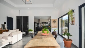 A modern living room with a large wooden table, a sofa, and potted plants. - Lovely home in Saint-Nazaire (Saint-Nazaire)
