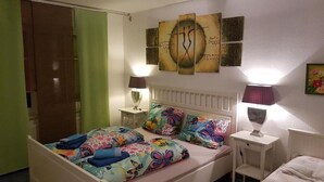 Ein Schlafzimmer mit einem Bett, zwei Nachttischen, einem Heizkörper und Kunstwerken an der Wand.