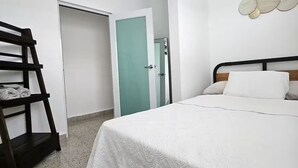 A bedroom with a bed, a ceiling fan, a wardrobe, and a door.