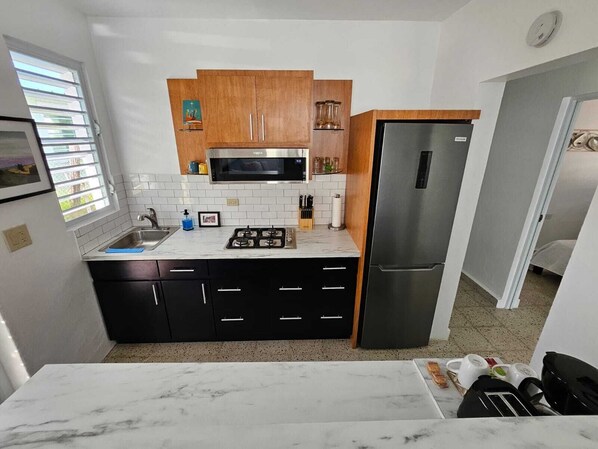 A compact kitchen with a microwave, stove, and refrigerator.