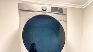 Una lavadora y secadora apiladas, con un panel de control y un reflejo visible.