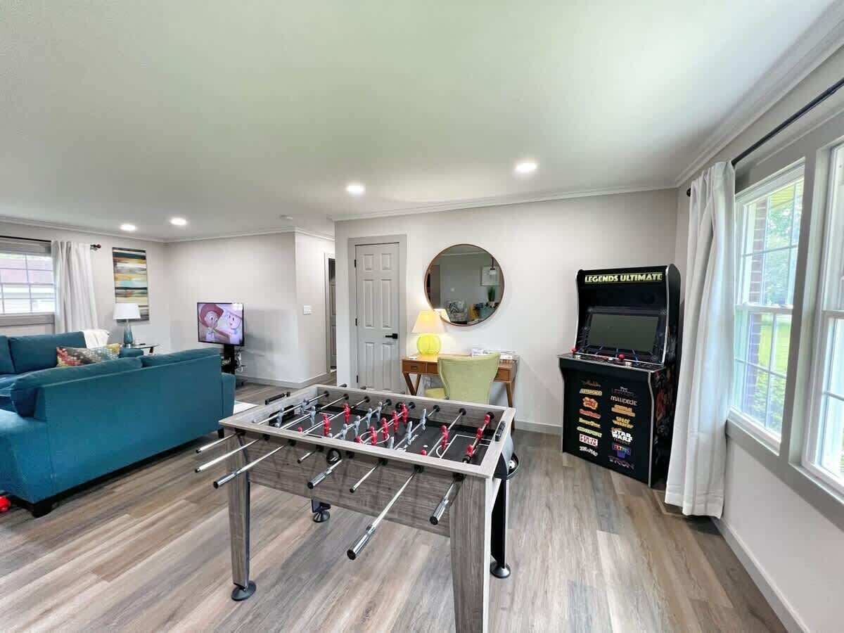 Una sala de estar con mesa de fútbol de mesa, un sofá, un televisor y un mueble para el fútbol de mesa.