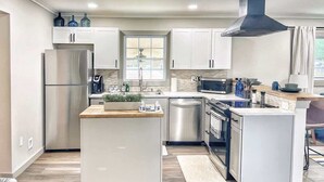 Una cocina moderna con armarios blancos, electrodomésticos de acero inoxidable y una isla central.