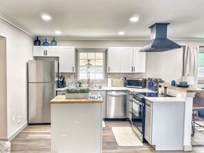 A modern kitchen with white cabinets, stainless steel appliances, and a central island.
