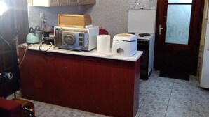 Una cocina compacta con techo de madera, piso de baldosas y servicios básicos como refrigerador, estufa y armarios.