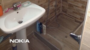 Baño con lavamanos, cepillo de dientes, jabonera y ducha.