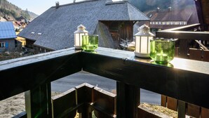 Een balkon met uitzicht op huizen en een bebost berglandschap op de achtergrond.