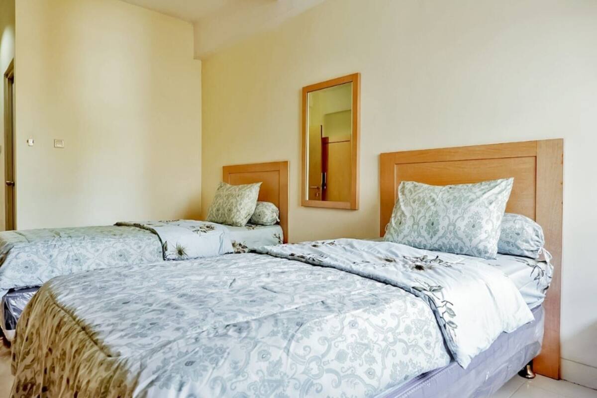 Habitación de hotel con dos camas, cada una con ropa de cama estampada y cabeceros de madera.