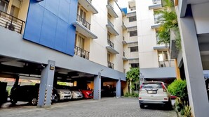 Un edificio residencial de varios pisos con zona de estacionamiento techada.