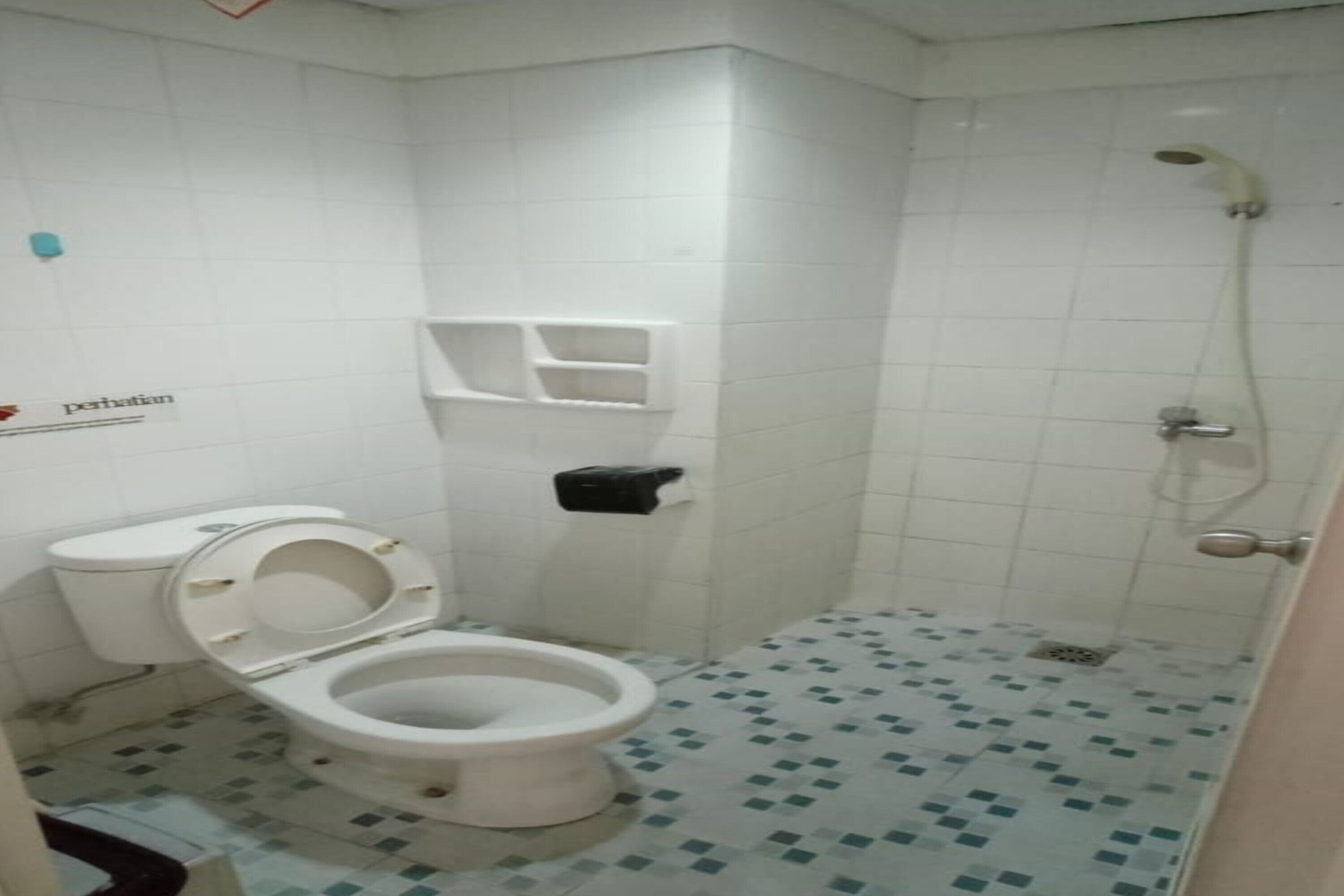A small bathroom with a toilet, a shower, and a tiled floor.