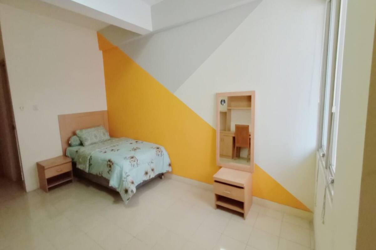 Un dormitorio con cama, mesitas de noche, cómoda y espejo.