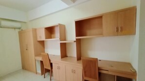 Una habitación con un escritorio de madera, dos sillas y un armario.