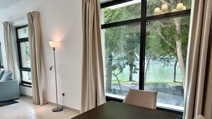 Une pièce moderne avec une grande fenêtre, une table à manger avec un boîte de mouchoirs, une lampe et un canapé.