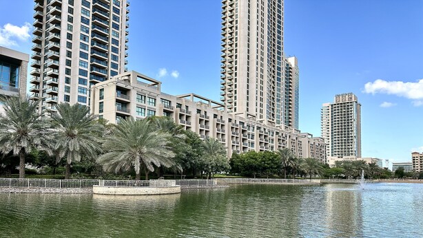 Un immeuble résidentiel de grande hauteur doté de balcons, situé au bord de l’eau et agrémenté de palmiers.