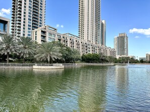 A high-rise residential building with balconies, a waterfront, and palm trees. - Lux BnB Travo Tower I Private Garden I Lake View (Dubai)