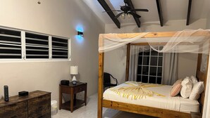 Een slaapkamer met een houten bed, nachtkastje, bureau en kledingkast.