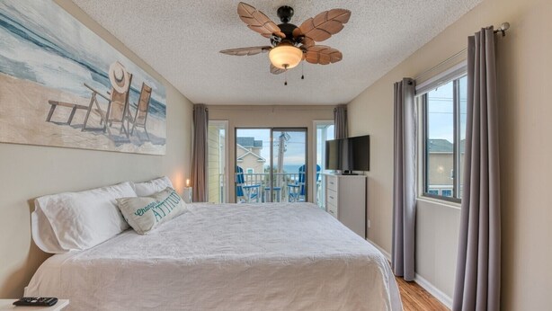 Een slaapkamer met een groot bed, een plafondventilator, een televisie en een balkon met uitzicht.
