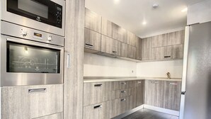 A modern kitchen with built-in appliances, wooden cabinetry, and a dark wood floor.