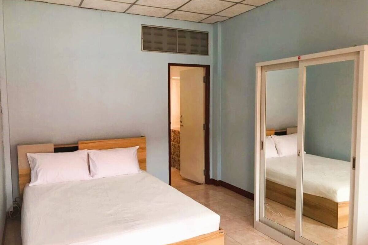 Une chambre à coucher comprenant un lit, une armoire et une porte donnant sur une autre pièce.