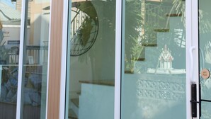 Un edificio con grandes puertas y ventanas de vidrio, un picaporte blanco y un pequeño accesorio de luz blanca en la pared.