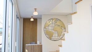 Un área de recepción con un escritorio de madera, un mapa del mundo como decoración de pared y lámparas colgantes.
