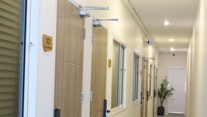 Un pasillo con puertas de madera, letreros con números y una planta en maceta.