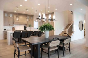 Una cocina moderna con una isla central, iluminación colgante y una escalera que sube a un nivel superior.